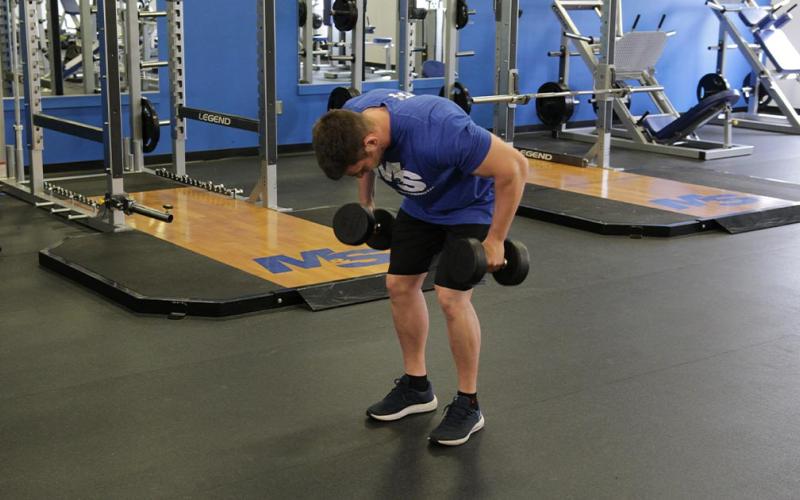 Fit man doing palms in bent-over dumbbell row in the gym.