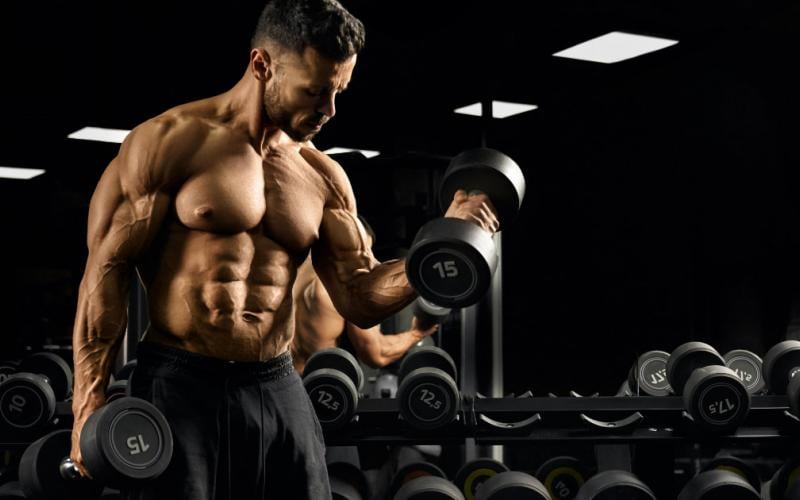 Man doing dumbbell bicep curls in gym.