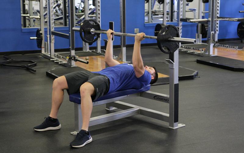 Fit man doing a reverse grip bench press in the gym.