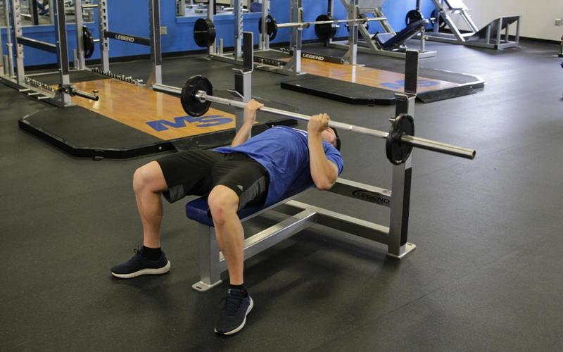 Fit man doing a reverse grip close grip bench press at the gym.