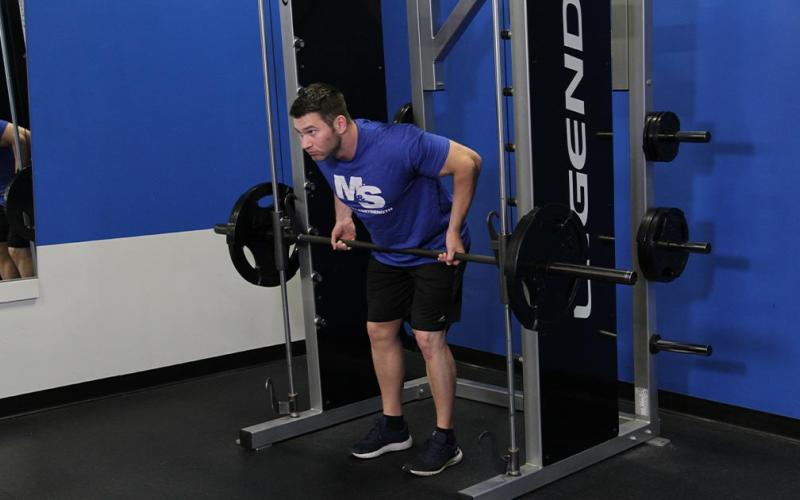 Fit man doing a reverse grip smith machine bent-over row in the gym.