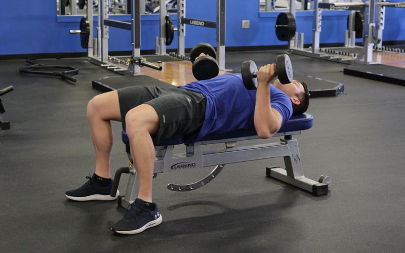Fit man doing a reverse grip dumbbell bench press in the gym
