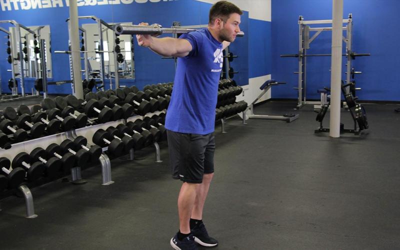 Fit man doing a rocking standing calf raise at the gym.