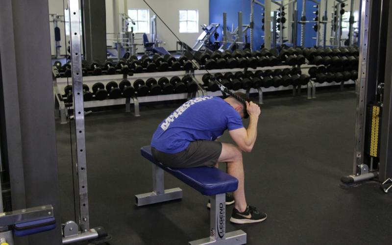 Fit man doing a seated cable crunch in the gym.