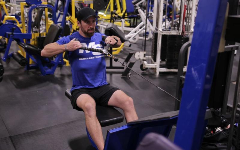 Fit man doing a seated high cable row in the gym
