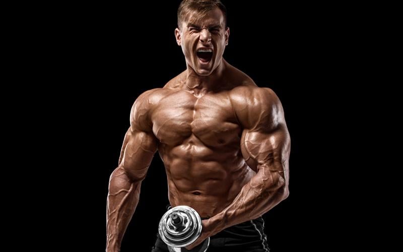 Shirtless muscle man holding dumbbell screaming