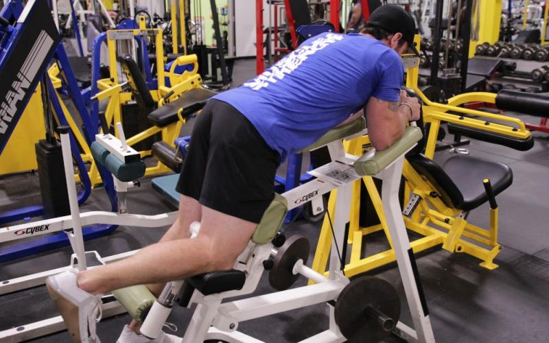 Fit man doing a single leg curl in the gym