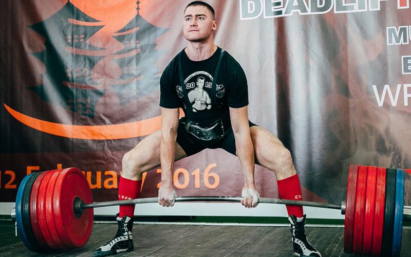Strong man doing a deadlift at powerlifting meet in Russia