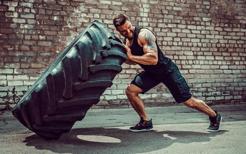 Strong man flipping tire outside