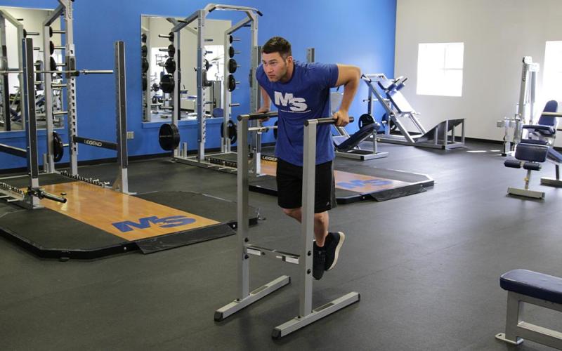 Fit man doing a tricep dip in the gym.