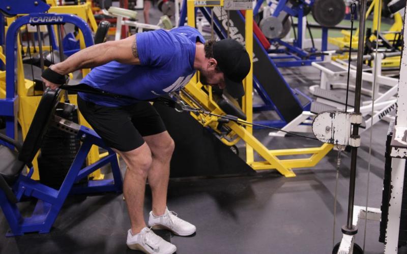 Fit man doing Two-Arm Cable Tricep Kickbacks in the gym