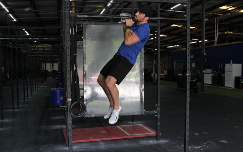Fit man doing a v-bar pull up in the gym