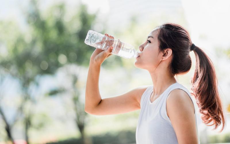 Woman drinking water outdoors.