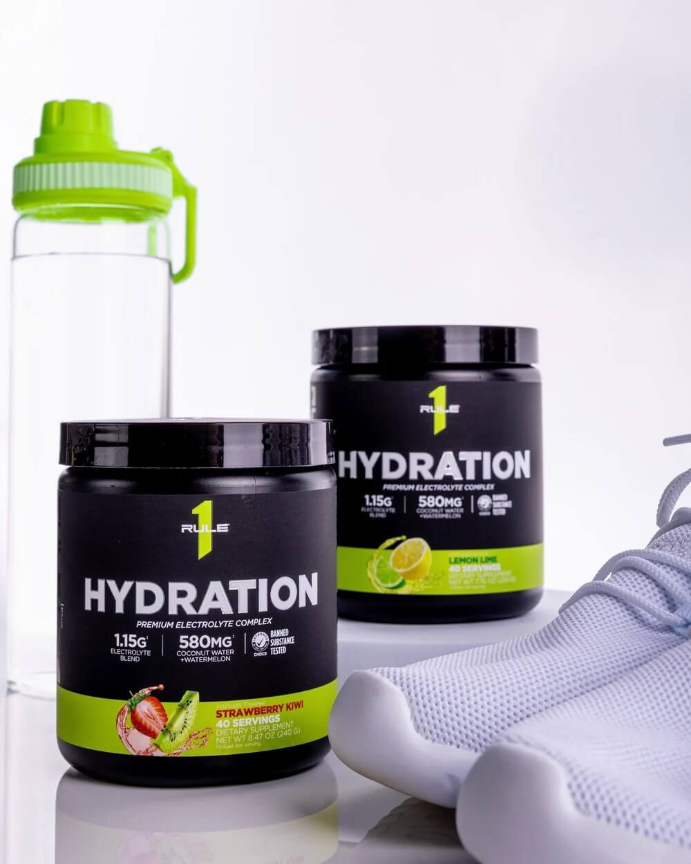 Rule 1 Hydration Premium Electrolyte Complex powder in Strawberry Kiwi and Lemon Lime flavors displayed with a white water bottle and athletic socks